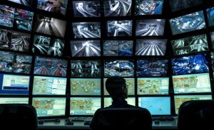 A man watches the screens of multiple CCTV monitors to view CCTV footage.