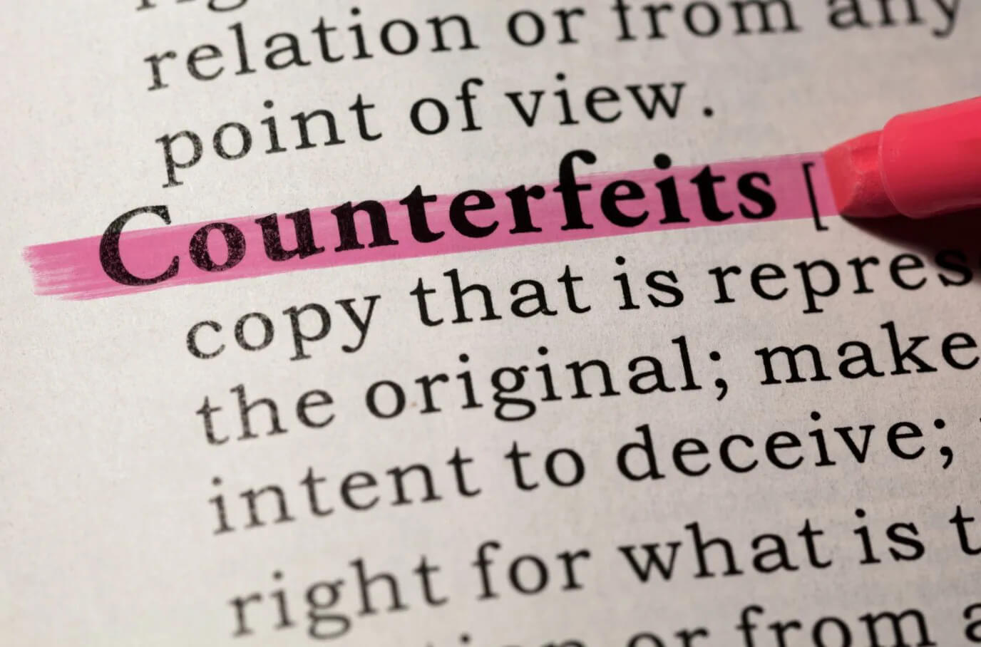 Counterfeit definition being highlighted in a dictionary