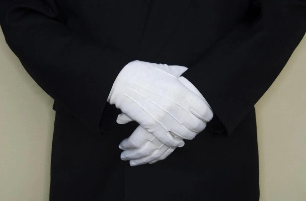 Zoomed in doorman's hands which are covered by white gloves